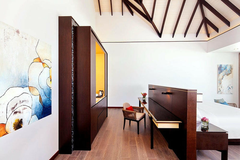 A villa desk at Radisson Blu Maldives, dark timber unit and blue abstract prints under open beams.