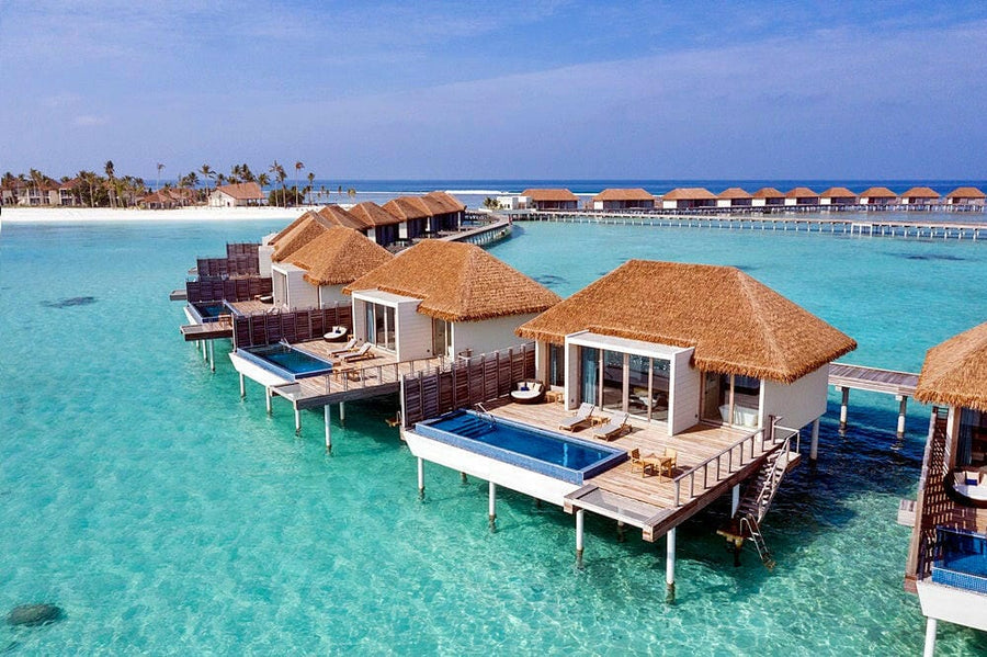 Radisson Blu Maldives from the air, thatched overwater villas with pools above clear turquoise water.