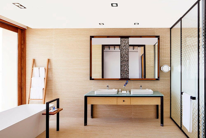 A villa bathroom at Radisson Blu Maldives, twin basins on a green glass counter by a glass shower.
