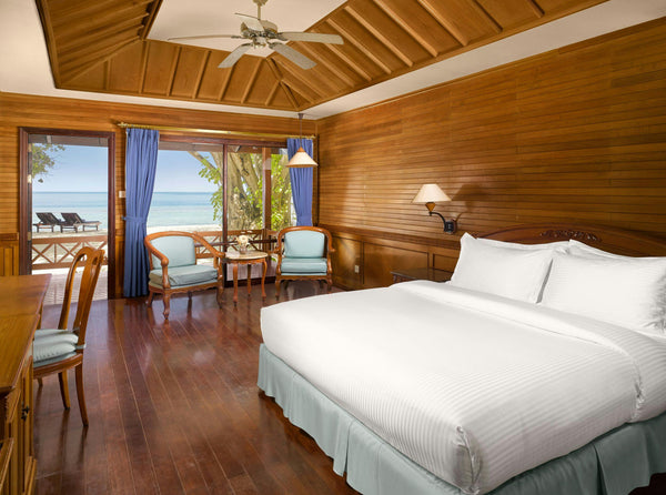 Bedroom of a beach villa at Royal Island, timber walls and doors open towards the sea