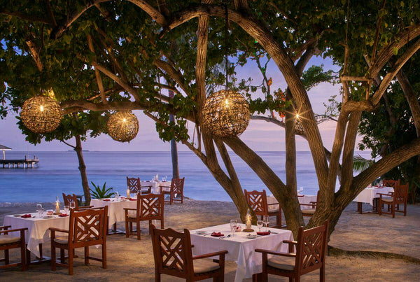 Tables set under lantern-hung trees beside the water at Raabondhi restaurant, Royal Island
