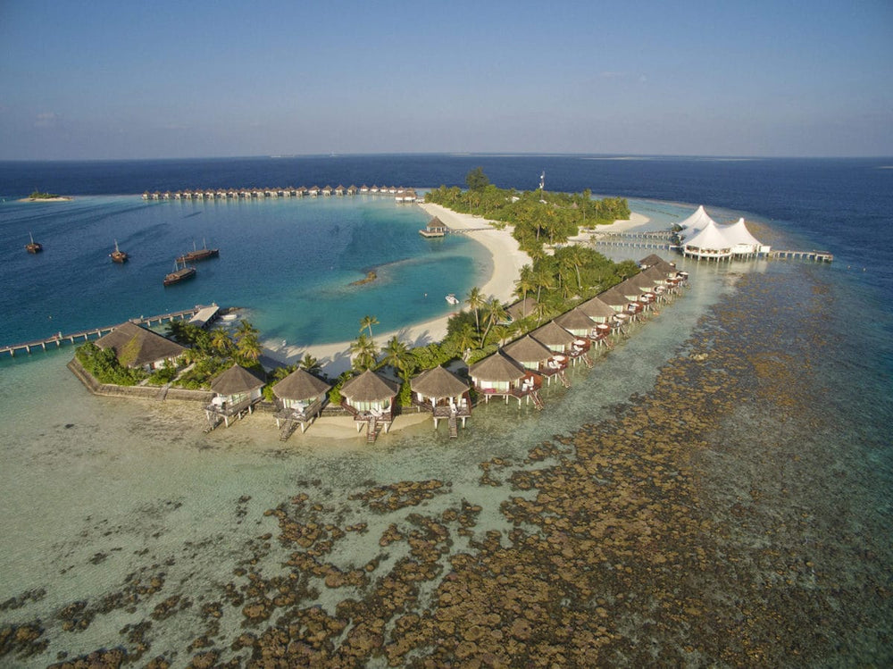 Safari Island from the air in North Ari Atoll, the reef running close around the island and bungalows along the shore