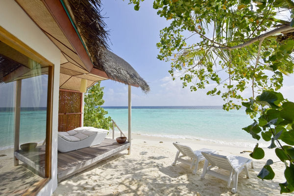 A thatched beach bungalow at Safari Island with its terrace looking straight out onto the beach and shallow turquoise water
