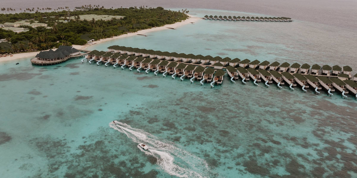 Siyam World from the air, a long line of overwater villas running out across the shallow reef flat