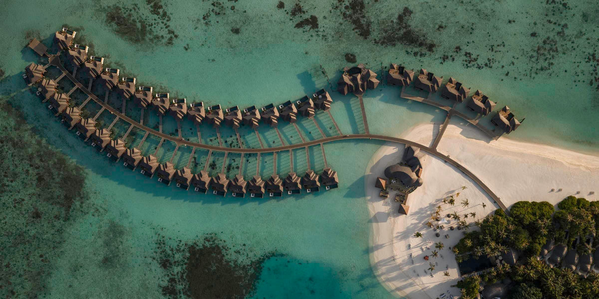 Sun Siyam Iru Fushi from the air, two curving rows of overwater villas reaching out from the beach