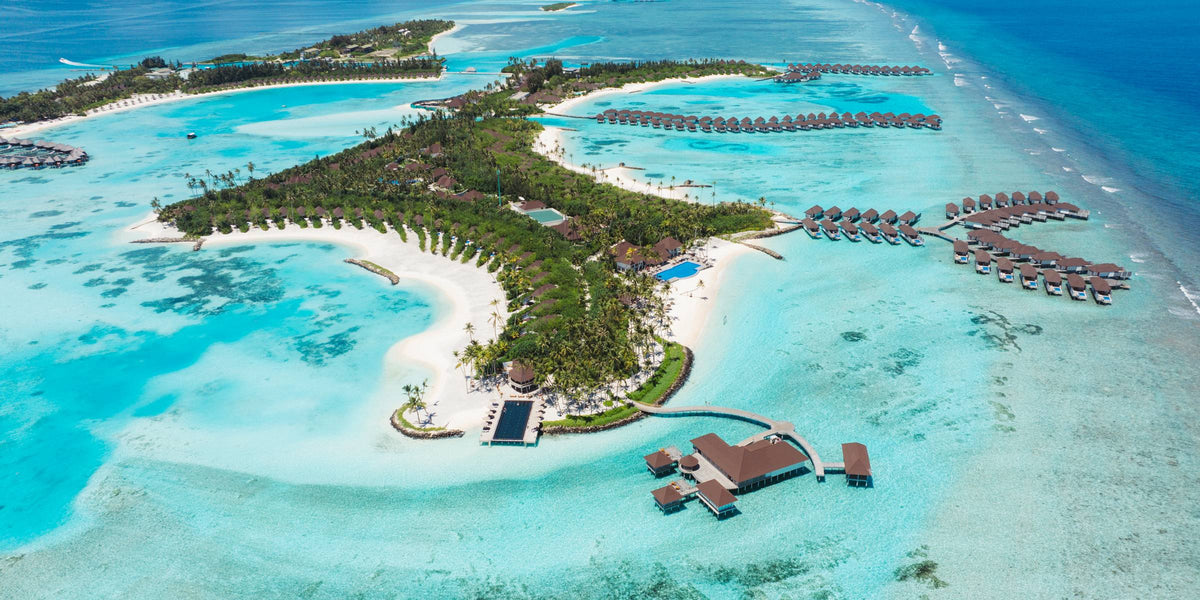 Sun Siyam Romance from the air, the beach curving round a shallow bay with the overwater villas beyond