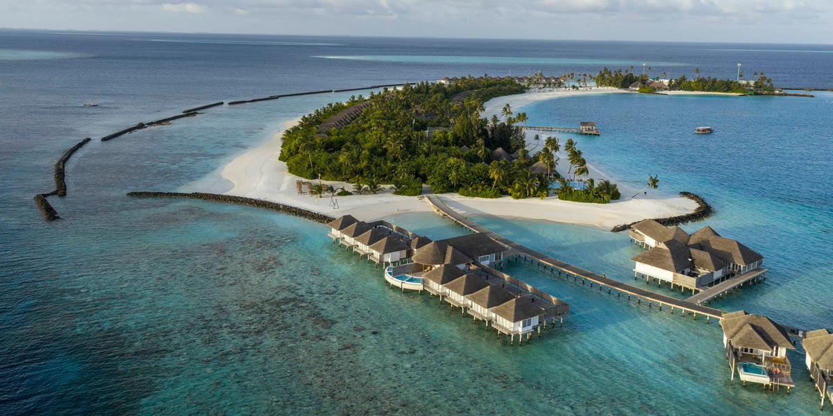 Sun Siyam Iru Veli from the air, the overwater villas curving away from the beach along their jetty