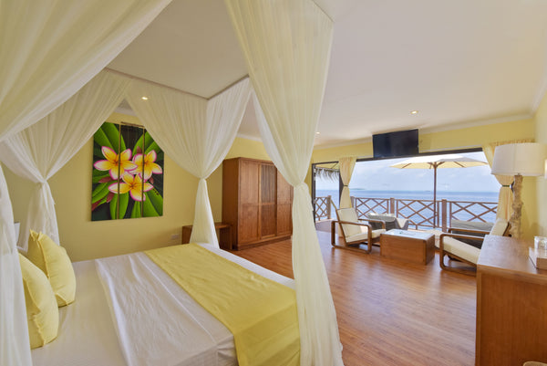 Bedroom of a superior water bungalow at Thulhagiri, doors opening to the lagoon
