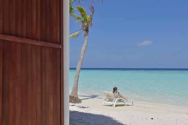 A lounger on the white sand beach at Thulhagiri Island Resort, North Malé Atoll