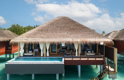 An overwater villa with a private pool at V Villas Maldives at Mirihi, a thatched roof over an open living deck and steps down into the lagoon.