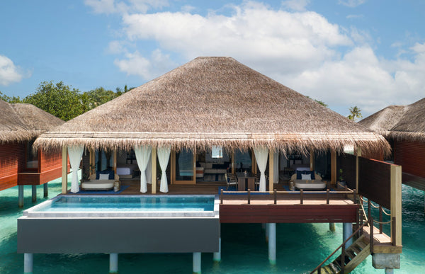 An overwater villa with a private pool at V Villas Maldives at Mirihi, a thatched roof over an open living deck and steps down into the lagoon.