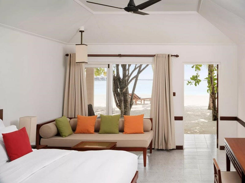 A Beach Villa lounge at Villa Nautica, green and orange cushions facing doors open to the sand.