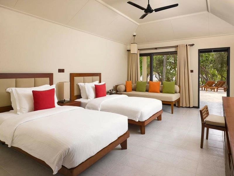 A twin room in a two bedroom beach villa at Villa Nautica, red and green cushions on white linen.