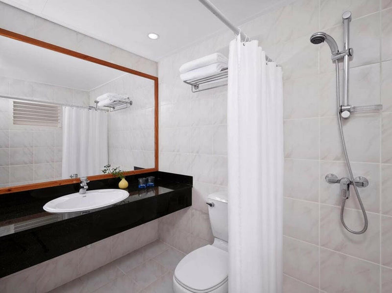 A villa bathroom at Villa Park Sun Island, a basin on a dark stone counter beside a curtained shower