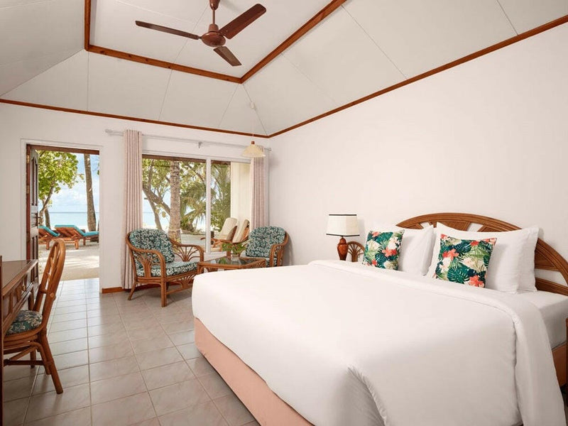 A beach villa bedroom at Villa Park Sun Island, turquoise cushions on white linen under a ceiling fan