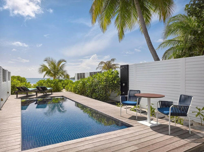A private pool at Villa Nautica, blue loungers on timber decking behind a white garden wall.