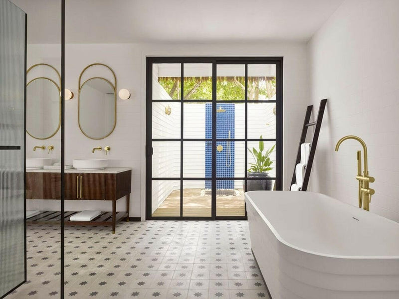 A villa bathroom at Villa Nautica, freestanding tub with a gold tap beside a glazed outdoor shower.