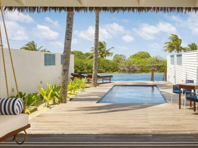 A villa plunge pool at Villa Nautica, a striped daybed on timber decking facing the jetty.