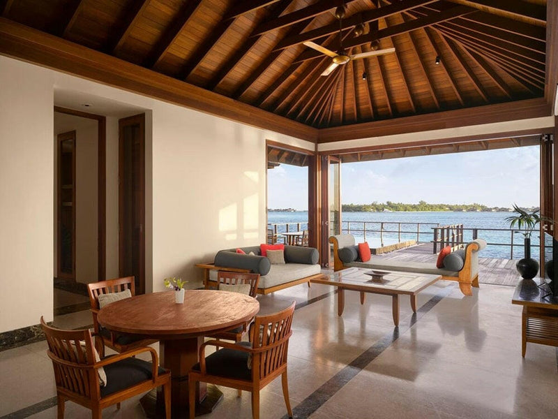 The living room of an ocean suite at Villa Nautica, a round timber table and rattan chairs facing the sea.