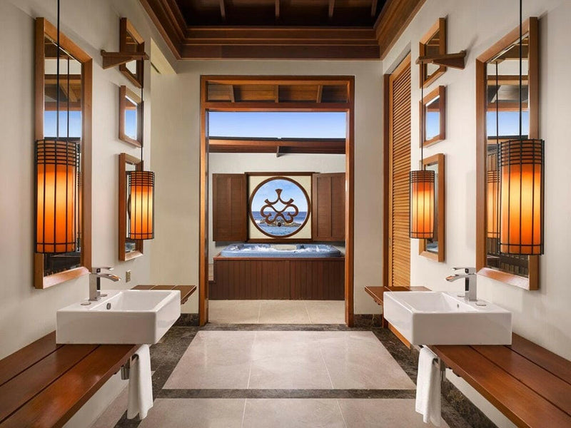 A suite bathroom at Villa Nautica, twin basins facing each other with a tub below a round window.