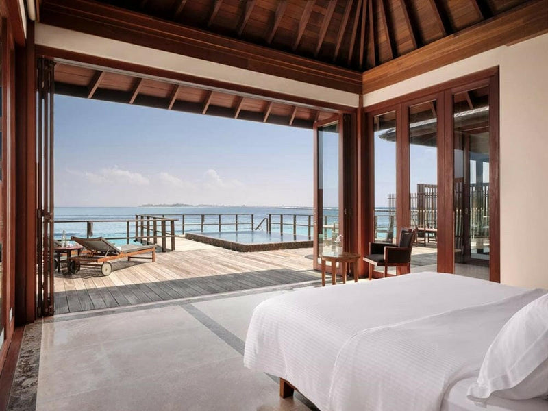 An ocean suite bedroom at Villa Nautica, a timber vaulted ceiling above doors open to the deck.