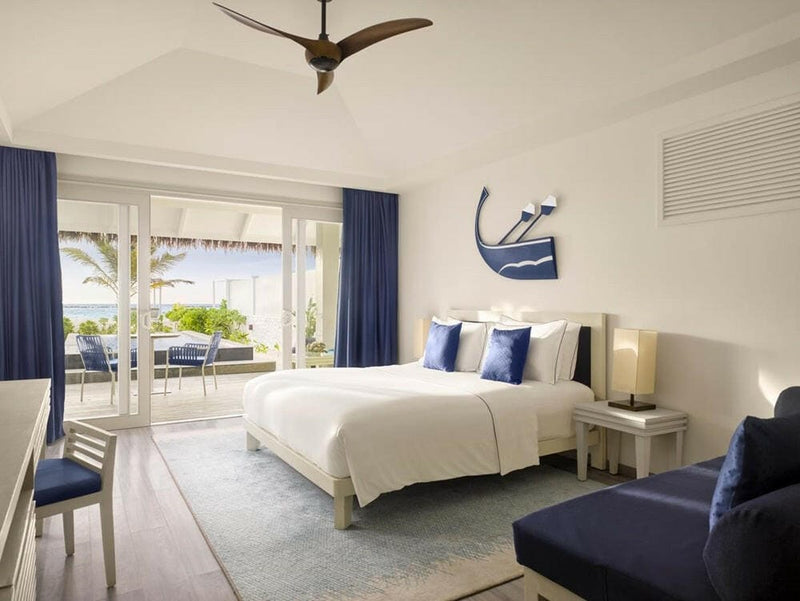 A villa bedroom at Villa Nautica, navy cushions and curtains with a fish study above the bed.