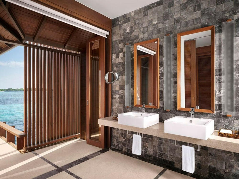A water villa bathroom at Villa Nautica, twin white basins set against a grey stone wall.