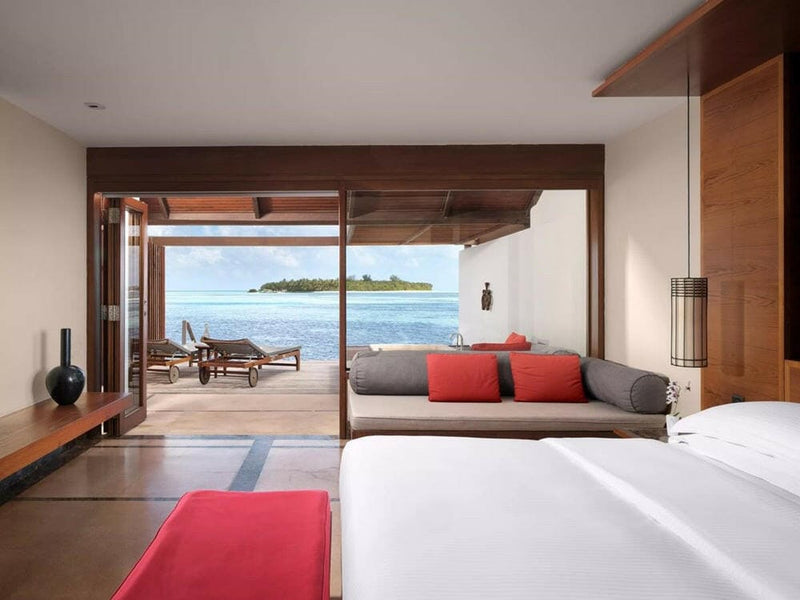 The view from a water villa at Villa Nautica, past a grey daybed to the reef and a distant island.