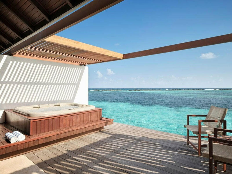 A whirlpool tub on a water villa deck at Villa Nautica, towels folded beside the open lagoon.