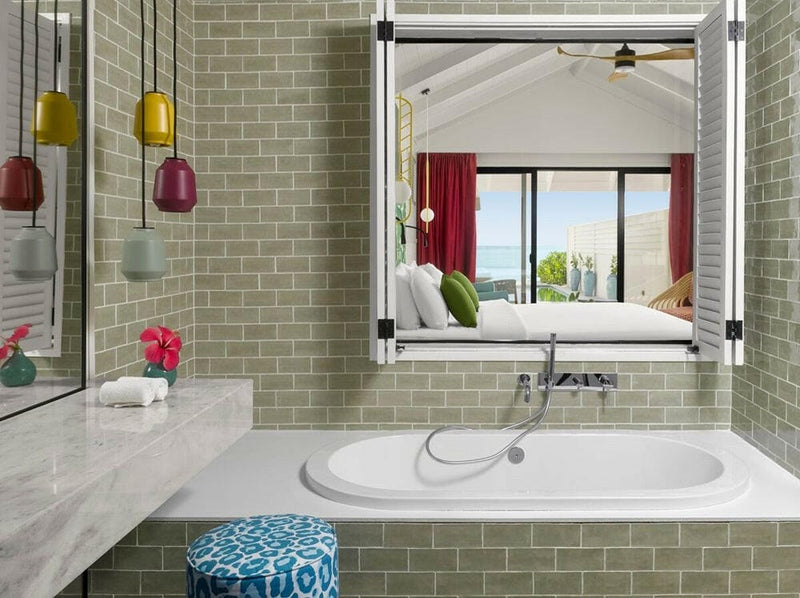A bath set into sage green tiles at Villa Park Sun Island, coloured pendants and pink flowers above