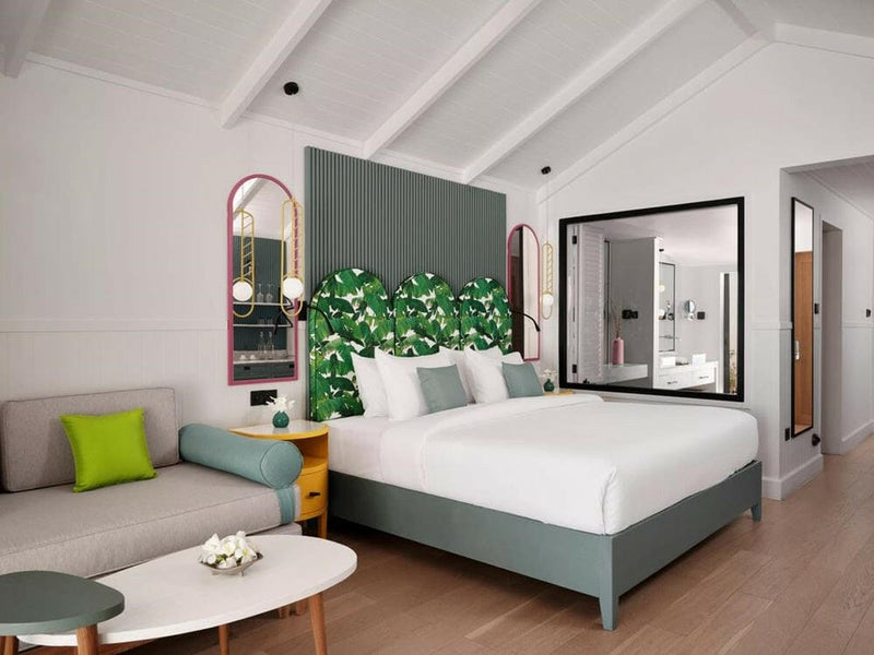 A villa bedroom at Villa Park Sun Island, an arched pink mirror on the wall and frangipani on the table