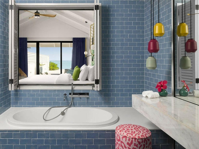 A sunken bath in blue tiles at Villa Park Sun Island, coloured glass pendants hanging above it