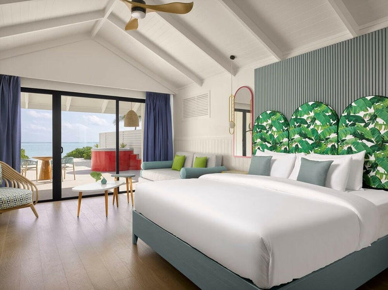 A beach villa bedroom at Villa Park Sun Island, a banana leaf headboard panel and a red side table