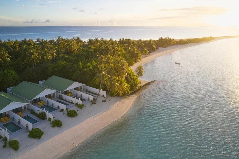 Villa Park Sun Island from the air at golden hour, villas set back under palms along the curving beach