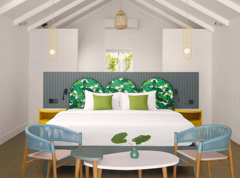 A pool villa bedroom at Villa Park Sun Island, two woven teal chairs at a round table beside the bed