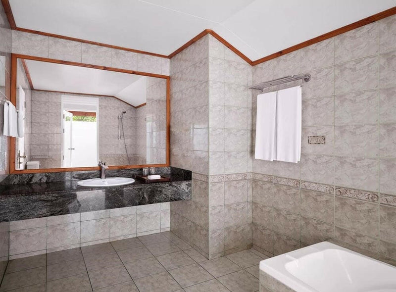 A villa bathroom at Villa Park Sun Island, a sunken tub set into dark stone against marbled walls