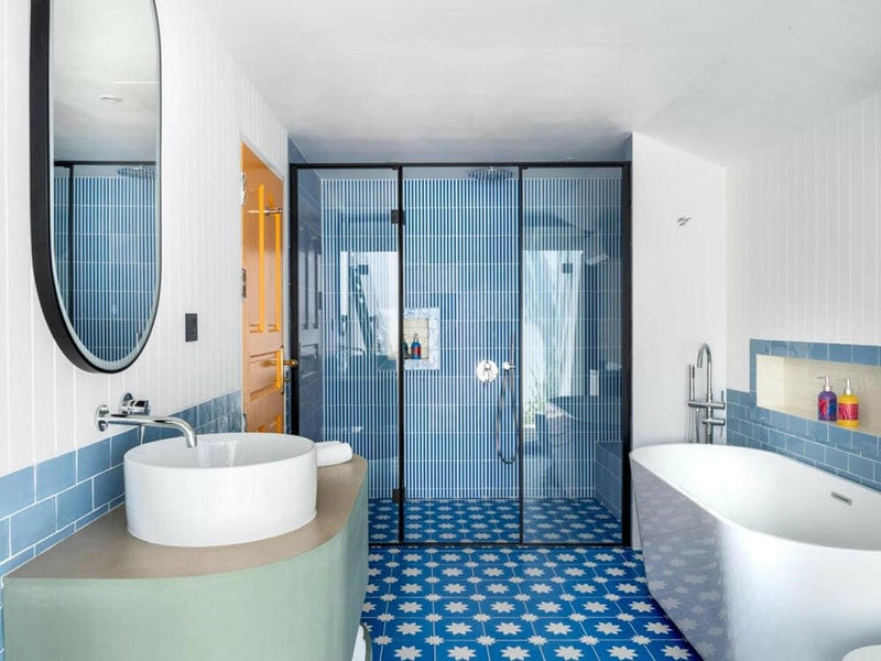 A villa bathroom at Villa Park Sun Island, a round basin and tall oval mirror beside a blue tiled shower