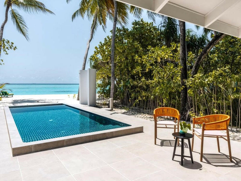 A private villa pool at Villa Park Sun Island, dark blue tiles and two orange woven chairs beside it