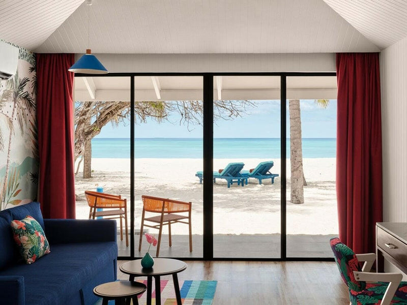 A villa sitting area at Villa Park Sun Island, a navy sofa and red curtains framing the beach outside