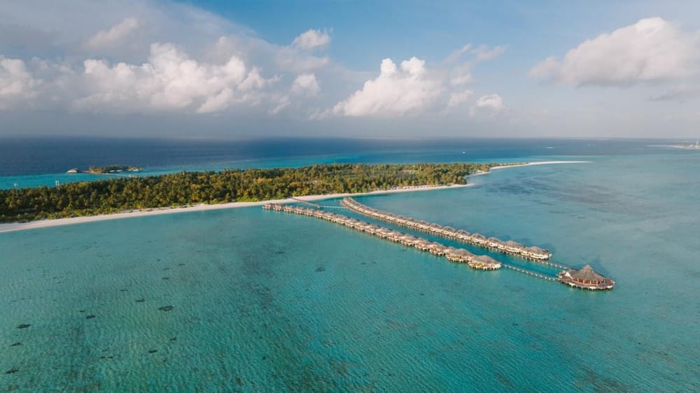 Villa Park Sun Island from the air, a long jetty of overwater villas reaching across the shallows