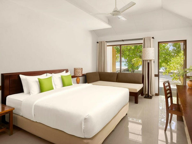 A beach villa bedroom at Villa Park Sun Island, lime green cushions and a long banquette by the window