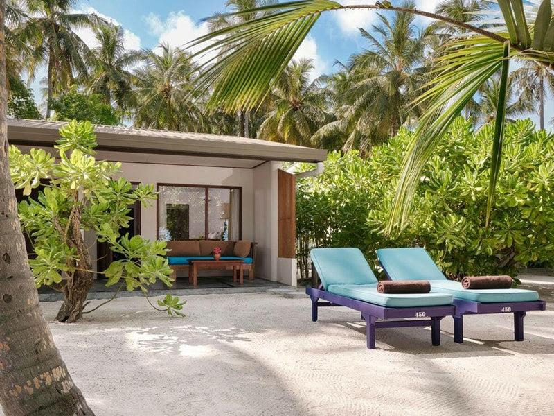 A beach villa at Villa Park Sun Island seen from the sand, blue and turquoise loungers outside it