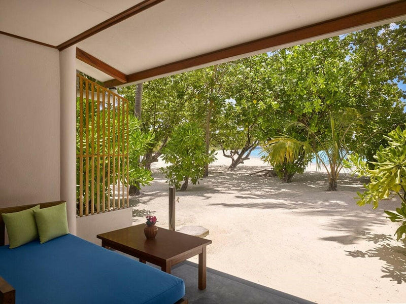 A shaded villa veranda at Villa Park Sun Island, a blue cushioned bench looking out through the trees