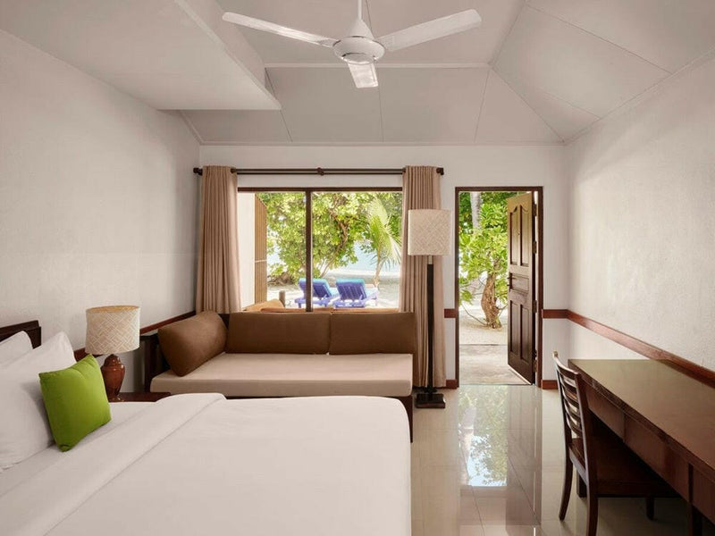 A beach villa interior at Villa Park Sun Island, a writing desk and sofa facing the curtained window