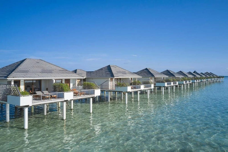 A long line of water villas at Villa Park Sun Island, grey roofs on stilts over the turquoise shallows