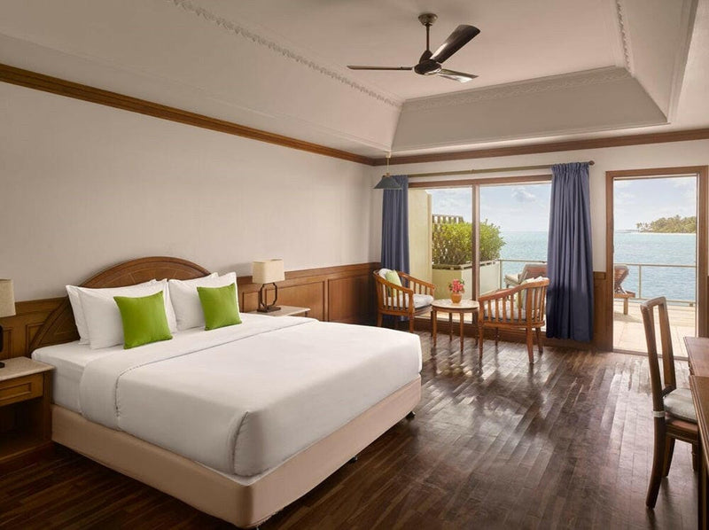 A water villa bedroom at Villa Park Sun Island, lime green cushions on the bed and blue curtains at the window