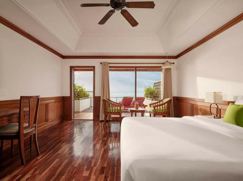 A water villa bedroom at Villa Park Sun Island, polished timber floors and a desk beside the balcony doors