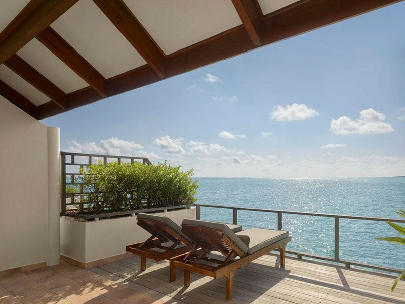 A water villa balcony at Villa Park Sun Island, a timber lounger and a planter of greenery facing the sea