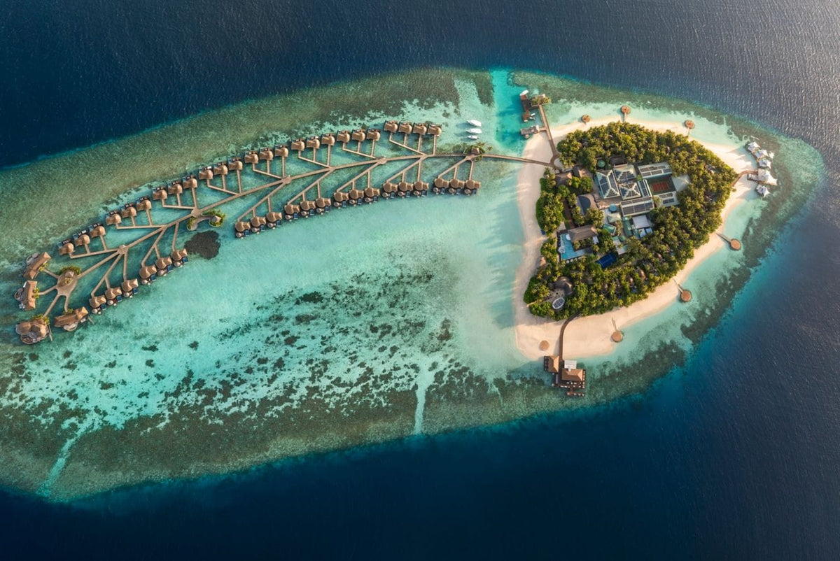 W Maldives from the air, the island ringed by overwater villas on both sides