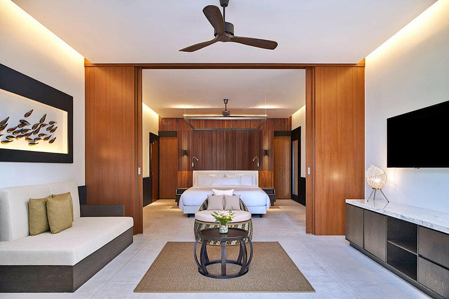 A villa bedroom at The Westin Maldives Miriandhoo, olive cushions on a built in sofa beside the bed.